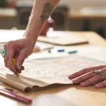 hands,of,young,craftswoman,with,yellow,crayon,drawing,on,page