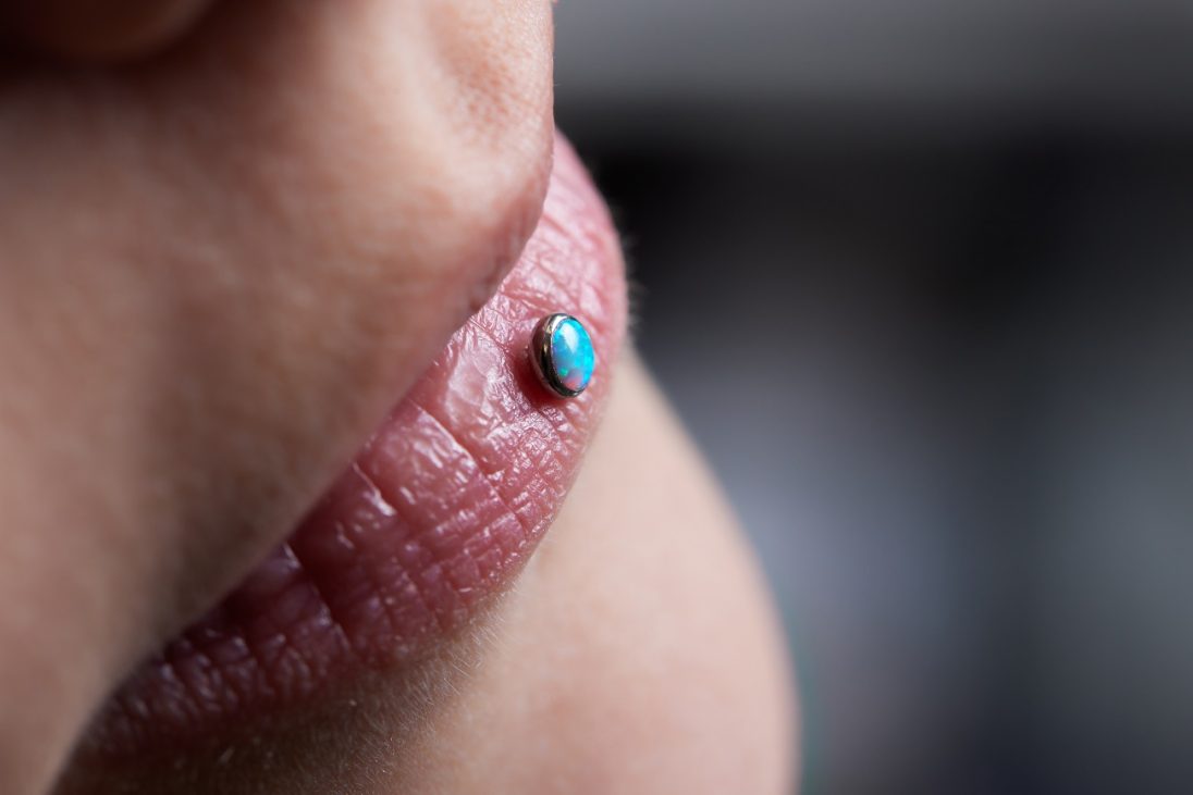 detail,of,a,labret,piercing,on,a,smiling,woman's,mouth.