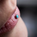 detail,of,a,labret,piercing,on,a,smiling,woman's,mouth.