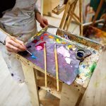 artist,draws,a,picture,in,an,apron,,easel,and,paint