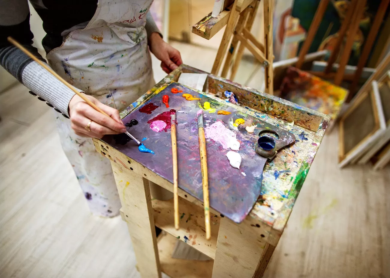 artist,draws,a,picture,in,an,apron,,easel,and,paint